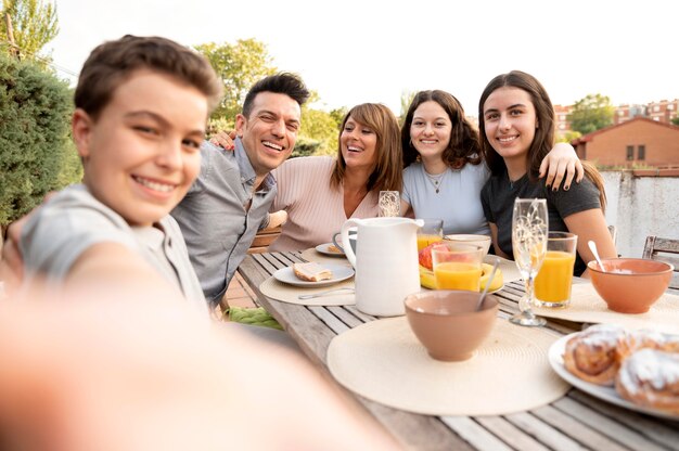 一緒に屋外で昼食をとっている家族のselfieを取る子供