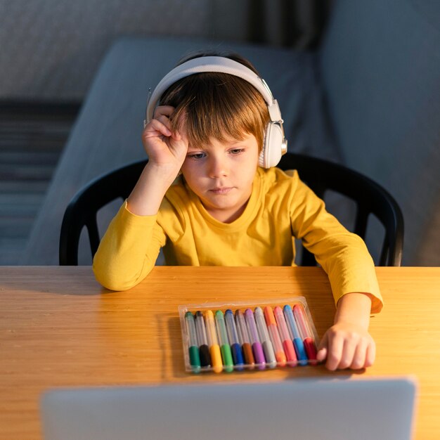 Child taking virtual courses and having colorful markers