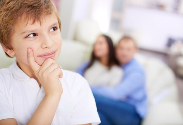 Child thinking with parents background