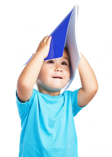 Child using a notebook as a hat