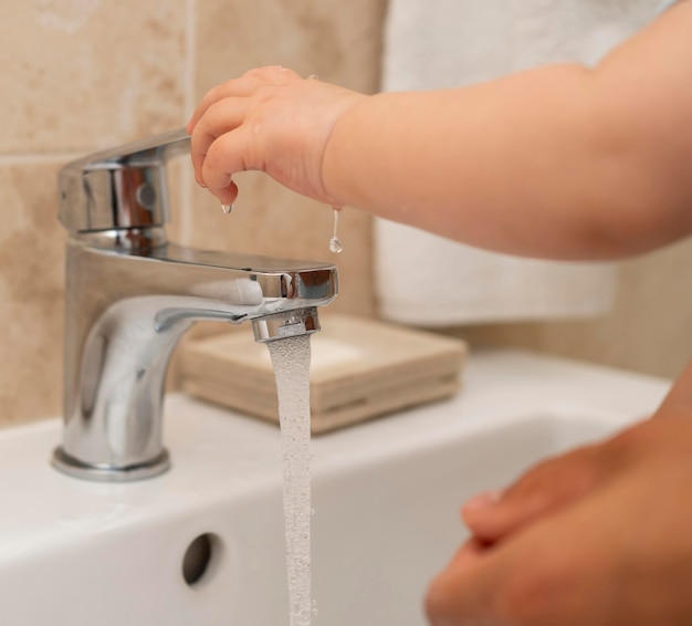 Child washing their hands with the help of parents