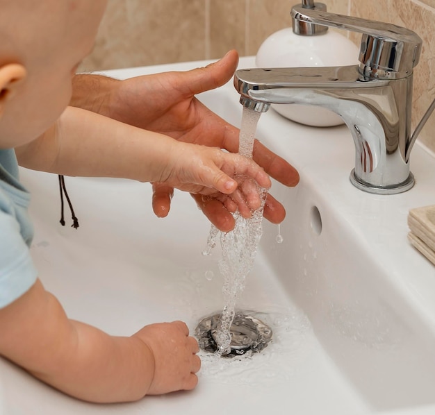 Child washing their hands with the help of parents
