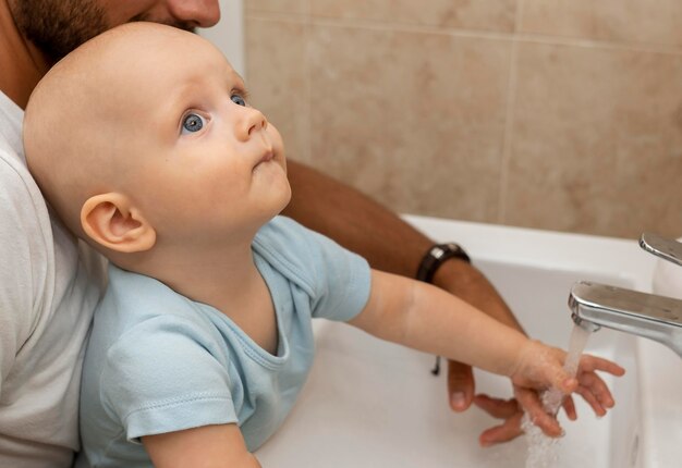 Child washing their hands with the help of parents