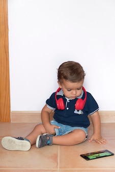 빨간 헤드폰과 진한 파란색 셔츠와 함께 휴대 전화에서 비디오를 보는 어린이