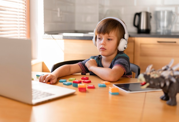 Child wearing headphones attending online courses