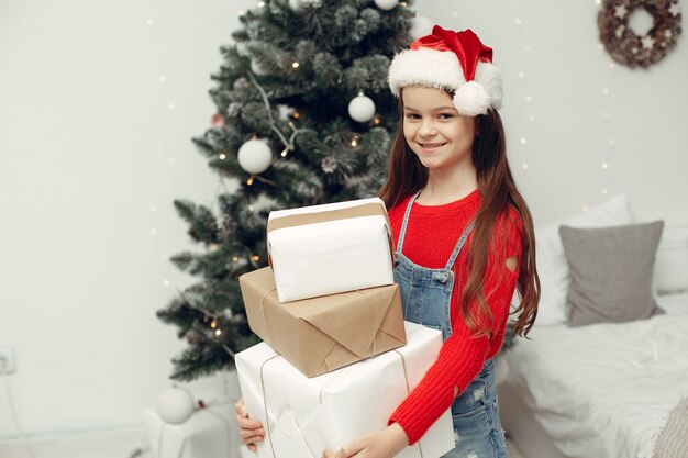 Child in a white sweater. Daughter sitting near Christmas tree.