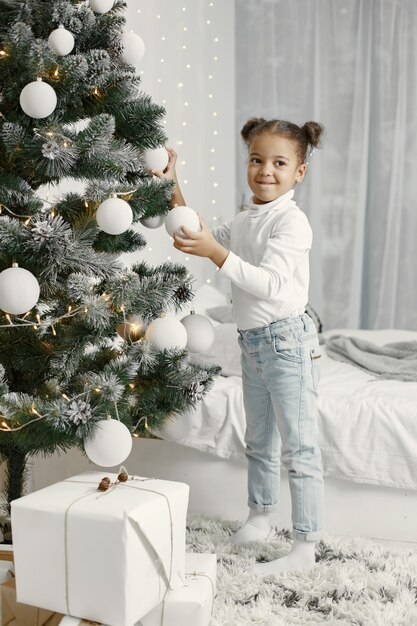 흰색 스웨터에 아이. 크리스마스 트리 근처에 서 딸입니다.
