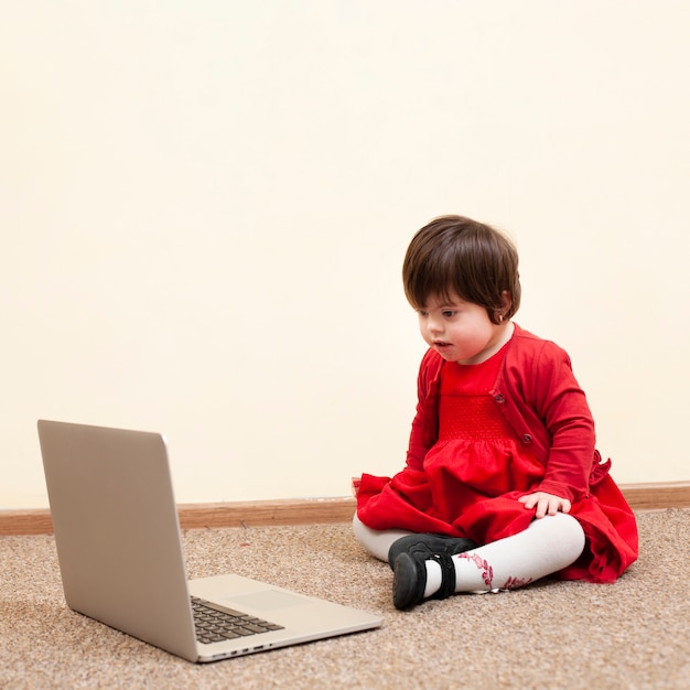 Free photo child with down syndrome looking at laptop