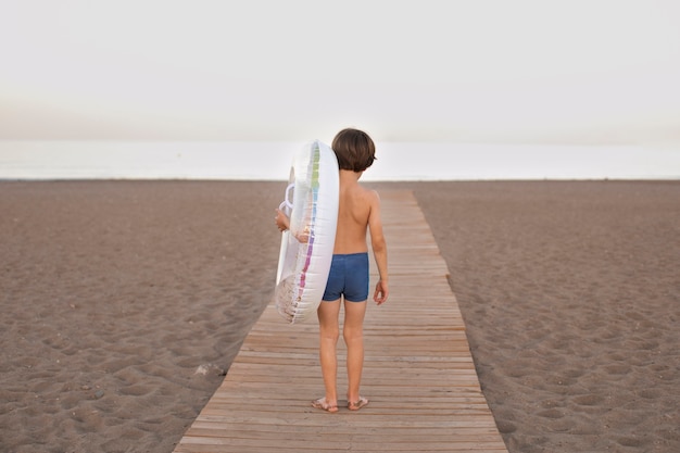 Foto gratuita bambino con galleggiante in riva al mare