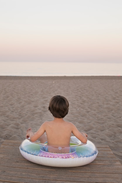 Foto gratuita bambino con galleggiante in riva al mare