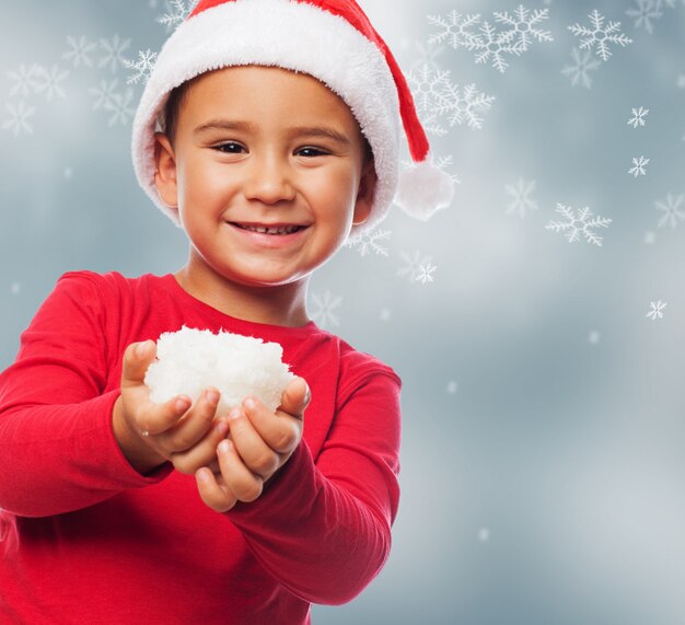 Child with snow in his hands and snow background