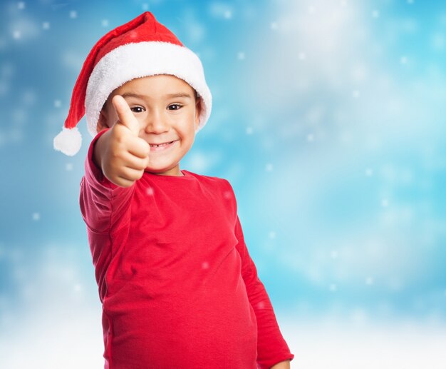 Child with thumb up in snow background