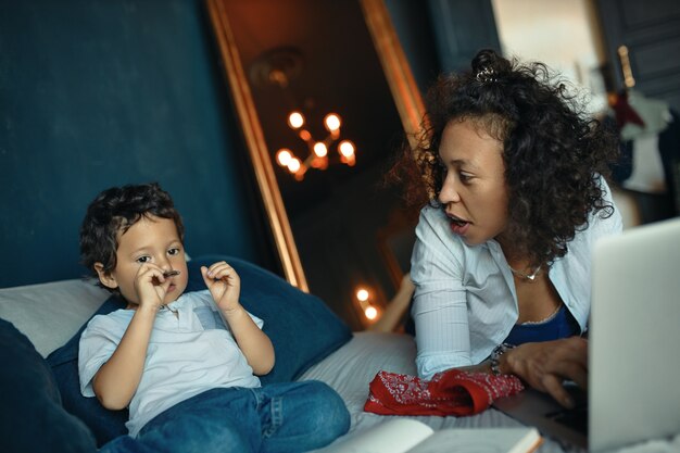 Free photo childhood, parenting, home schooling and online education concept. young mixed race mother using laptop while teaching numbers to her adorable preschool child