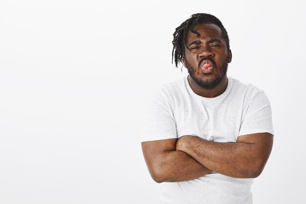 childish guy with braids posing against the white wall