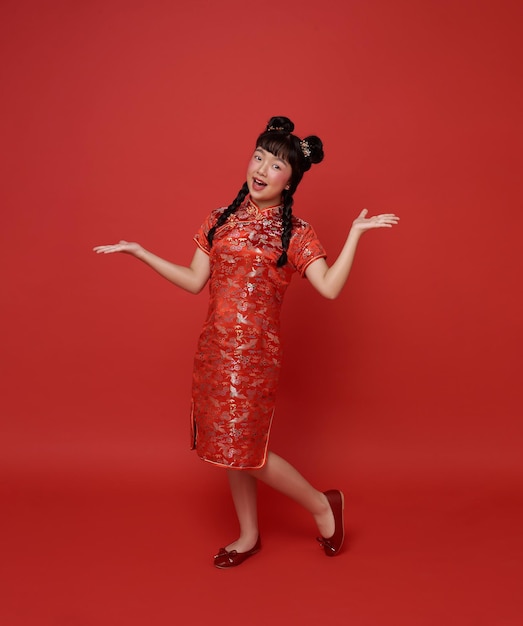 children asian girl in red traditional cheongsam qipao with gesture of welcome chinese new year 2024