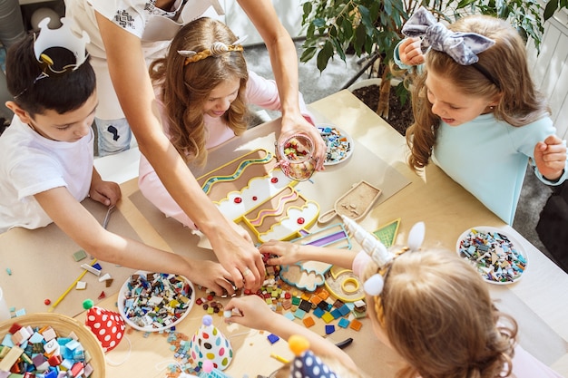 Free photo children and birthday decorations. boys and girls at table setting with food, cakes, drinks and party gadgets.