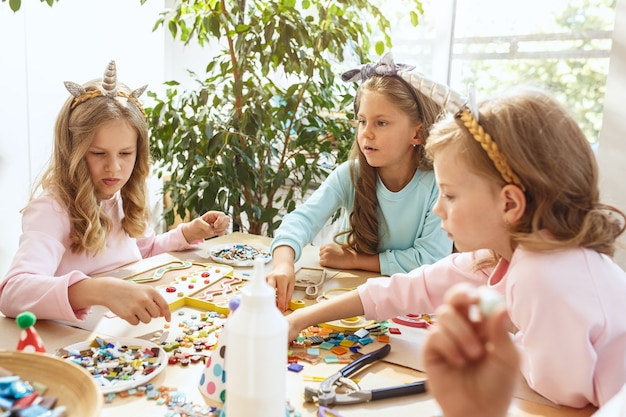 Bambini e decorazioni di compleanno. ragazzi e ragazze a tavola con cibo,  dolci, bevande e gadget per le feste.