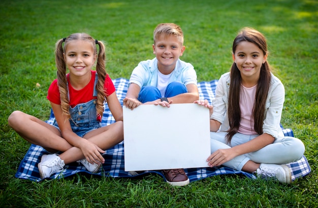 Children on blanket holding a poster in hands