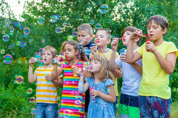 Дети пускают мыльные пузыри на улице. выборочный фокус. Premium Фотографии