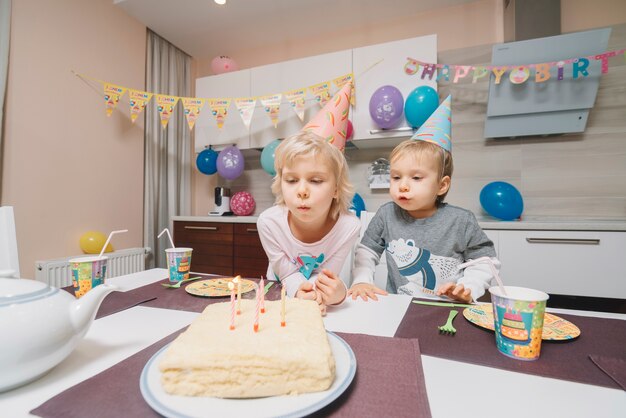 誕生日のケーキに蝋燭を吹く子供たち