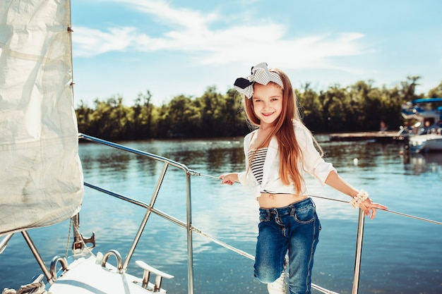 オレンジジュースを飲む海のヨットに乗っている子供たち。屋外の青い空に対して10代または子供の女の子。