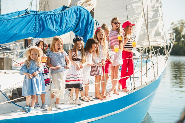 オレンジジュースを飲む海のヨットに乗っている子供たち。屋外の青い空に対して10代または子供の女の子。