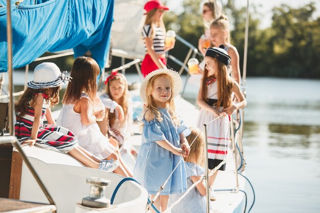 オレンジジュースを飲む海のヨットに乗っている子供たち。屋外の青い空に対して10代または子供の女の子。