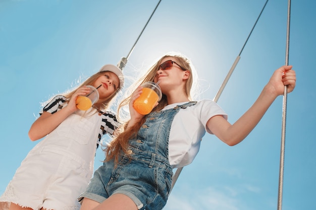 オレンジジュースを飲む海のヨットに乗っている子供たち