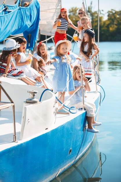 オレンジジュースを飲む海のヨットに乗っている子供たち。