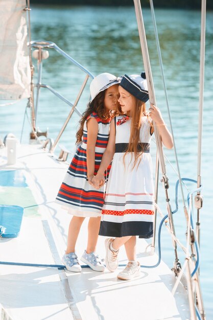 The children on board of sea yacht. The teen or child girls outdoor. Colorful clothes. Kids fashion, sunny summer, river and holidays concepts.