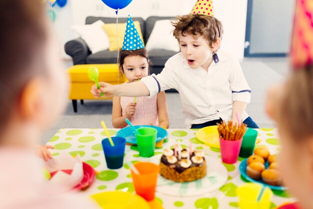 Children in colored caps eating snacks