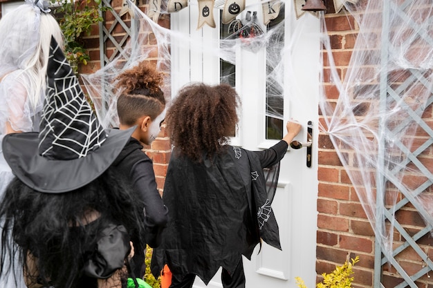 Children in costumes trick or treating at someone's house