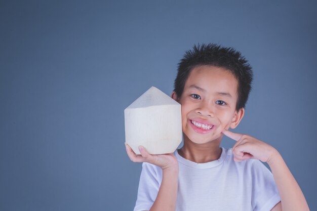 子供たちは灰色の背景にココナッツ水を食べる。