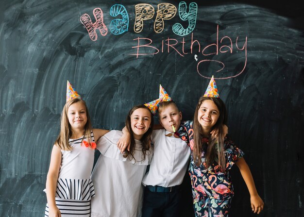 Children embracing near happy birthday writing