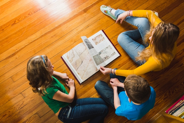 Children on floor turning over book pages 