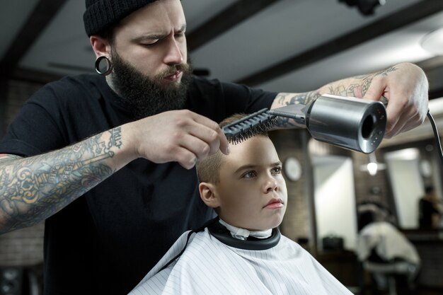 Детский парикмахер режет маленького мальчика в парикмахерской