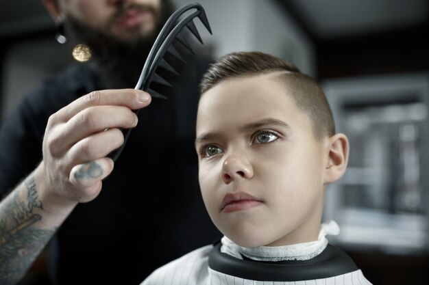 理髪店で小さな男の子を切る子供の美容師