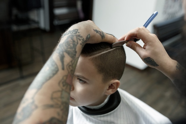 Free photo children hairdresser cutting little boy