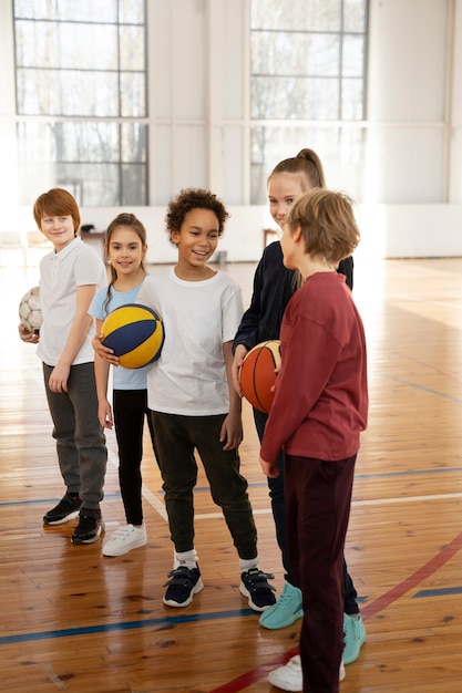 Children holding balls at gym full shot