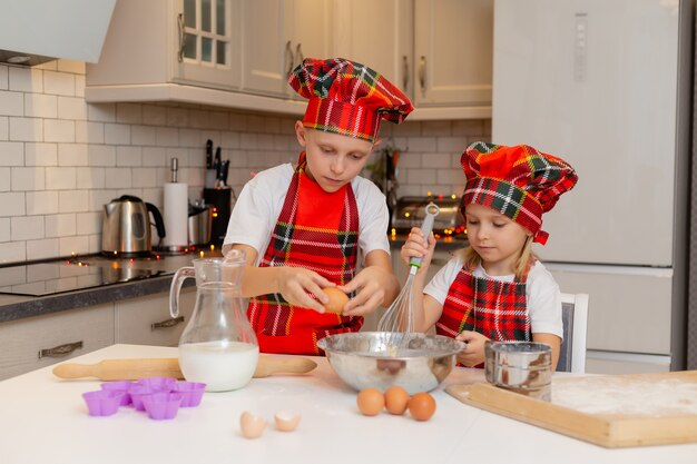요리사 의상을 입은 아이들은 크리스마스 패스트리를 위해 밀가루 우유 계란과 버터로 반죽을 준비합니다