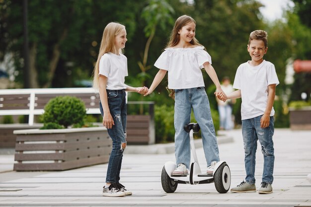 子供たちは晴れた夏の日に公園でホバーボードに乗ることを学ぶ