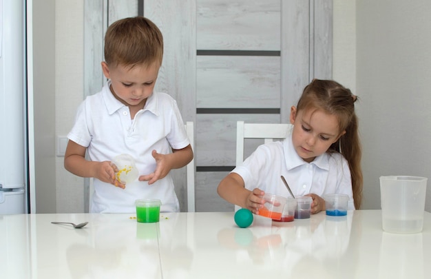子供たちは水と絵の具でさまざまな色を混ぜることを学びます。初期の開発。化学的および科学的実験または観察。 。教育科学の概念。セレクティブフォーカス。 Premium写真
