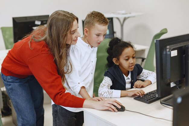 子供たちはコンピューターで働くことを学びます。テーブルに座っているアフリカの女の子。コンピュータサイエンスのクラスの男の子と女の子。