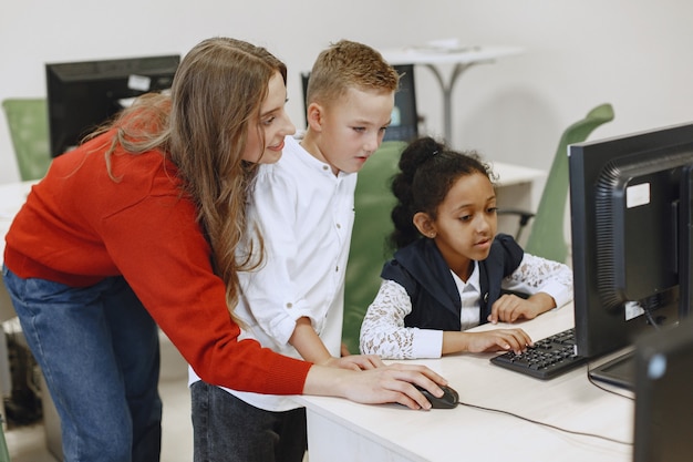 Дети учатся работать на компьютере. Африканская девушка сидит за столом. Мальчик и девочка в классе информатики.