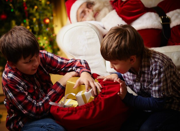 Children looking for their gifts with santa sleeping