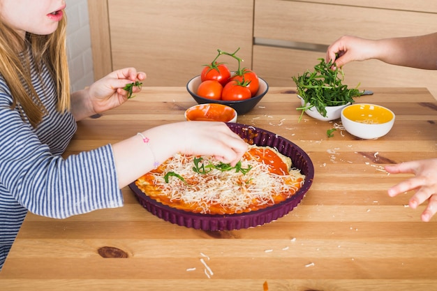 Free photo children making homemade pizza together in kitchen