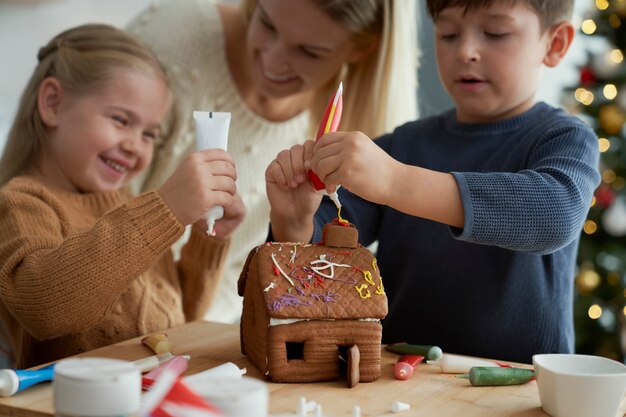 Children and mother decorating gingerbread house