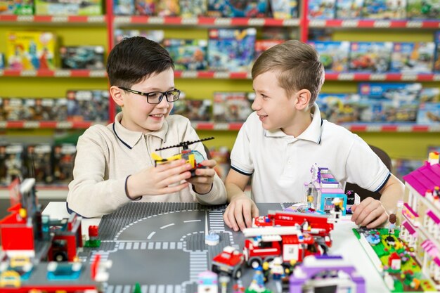 Дети играют в конструктор за столом. два мальчика играют вместе с цветными пластиковыми кубиками в игровом центре, школе.