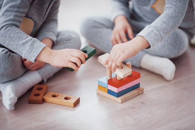 子供たちは子供部屋の床でおもちゃデザイナーと遊ぶ。カラフルなブロックで遊ぶ2人の子供。幼稚園教育ゲーム