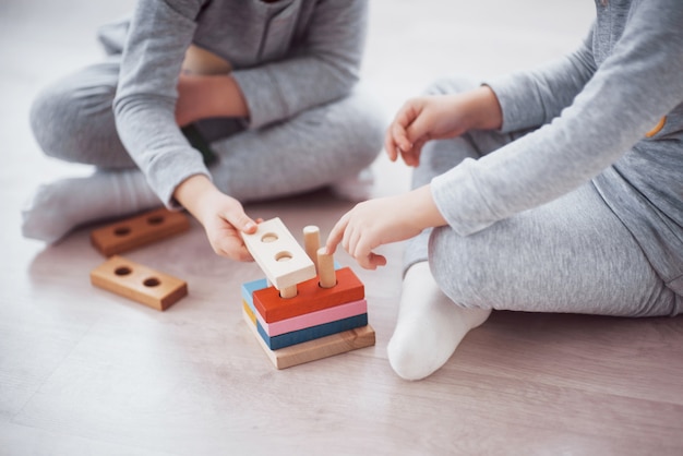 子供たちは子供部屋の床でおもちゃデザイナーと遊ぶ。カラフルなブロックで遊ぶ2人の子供。幼稚園教育ゲーム